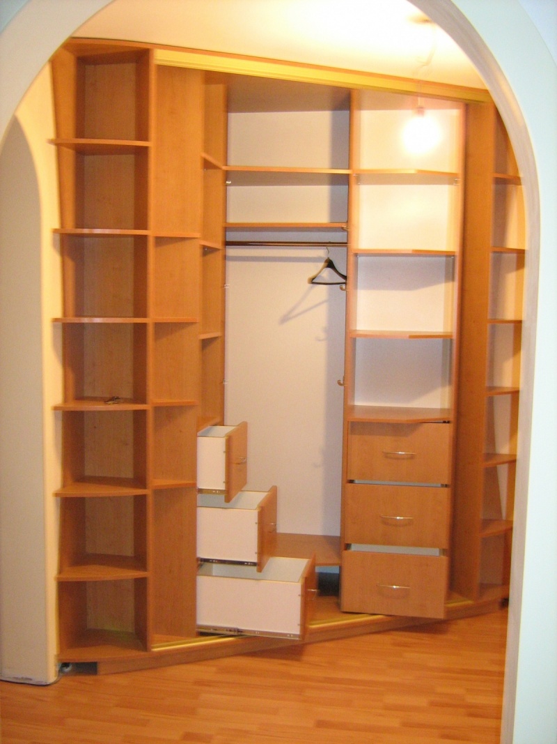 Armoire d'angle avec étagères ouvertes et cintres.